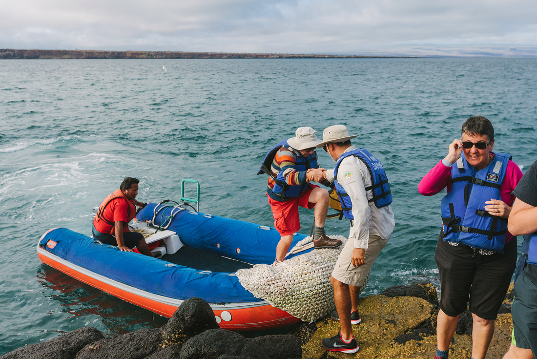 Tour leader helps traveller off panga boat, Galapagos Islands