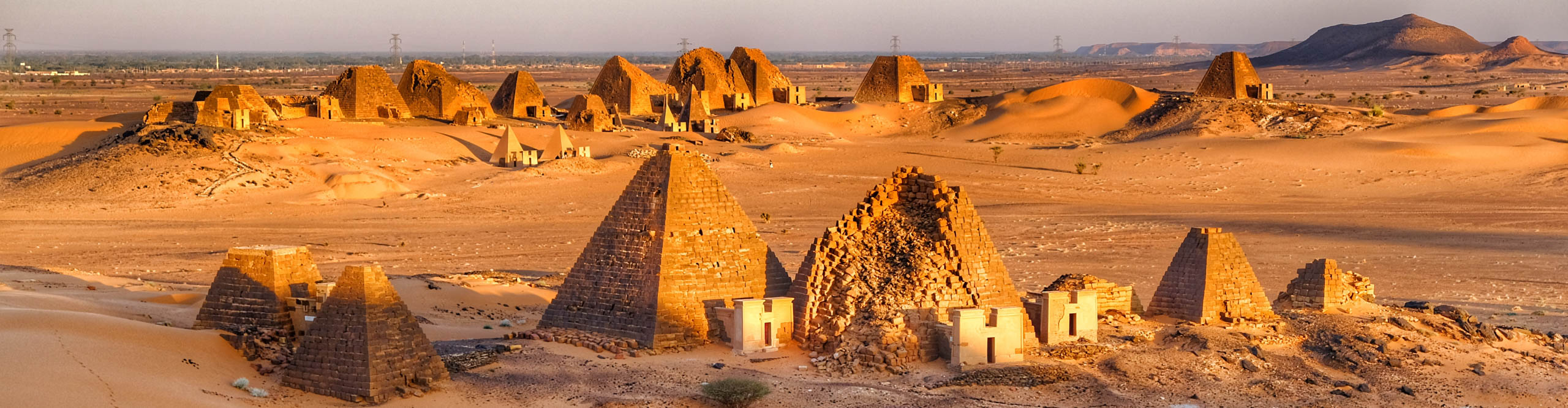 The Pyramids of Meroe at sunset glowing orange in the Sudanese desert