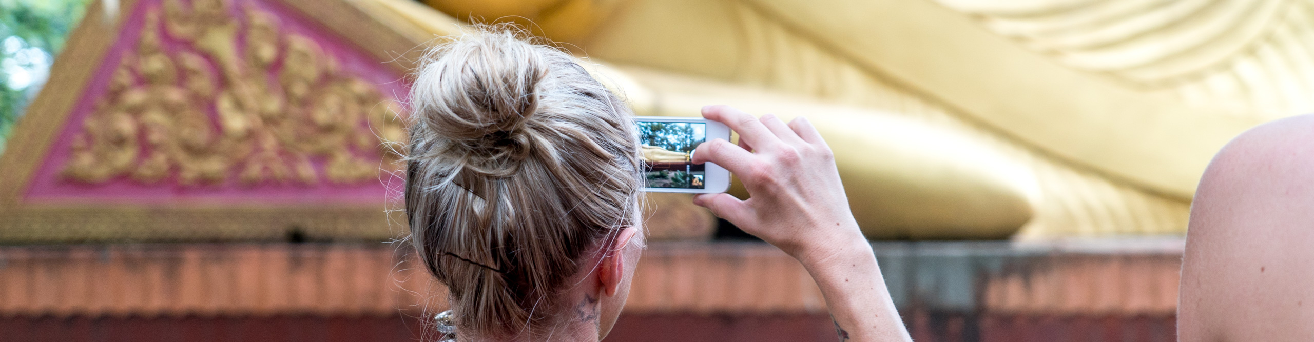 Woman taking picture of buddha on iPhone in Cambodia
