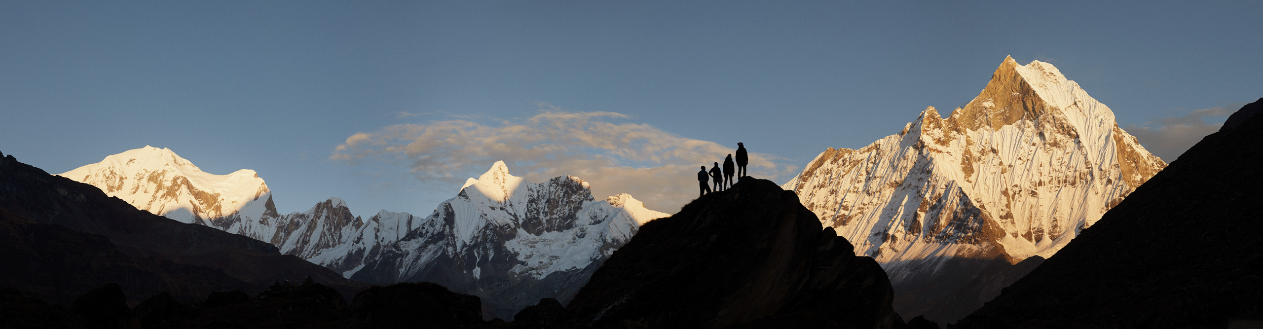 Silhouettes of four climbers in front of Everest at sunset on a clear day, Nepal 