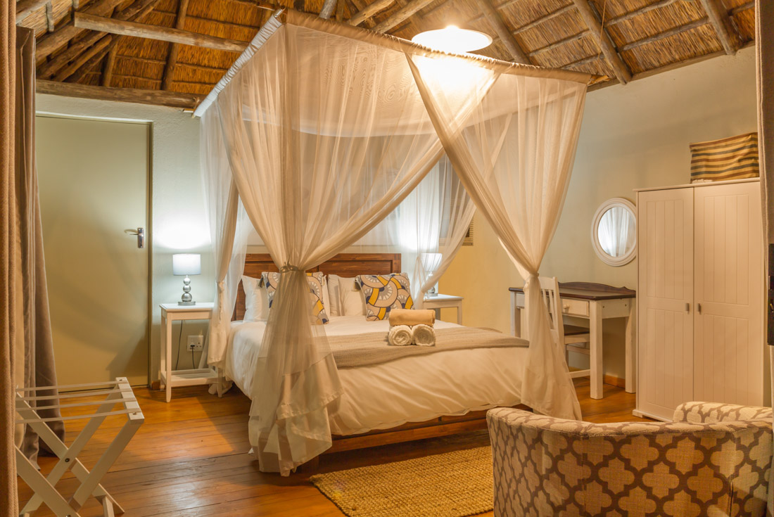Comfortable warm lit room with mosqutio netted four poster bed near Kurger National Park in South Africa
