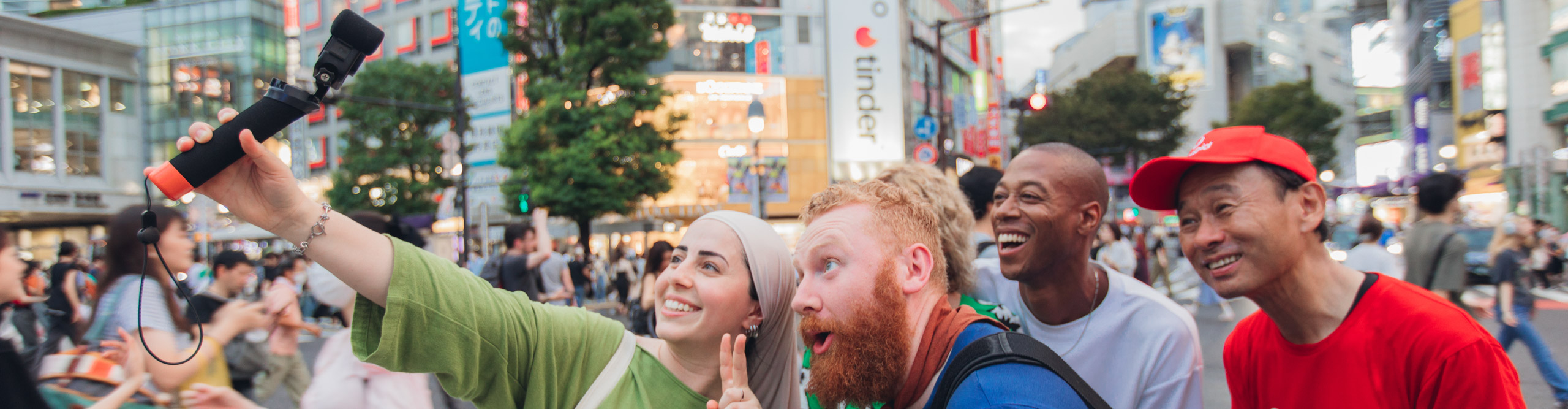 Group taking a selfie on a busy street in Tokyo with signs and bright lights in the background 