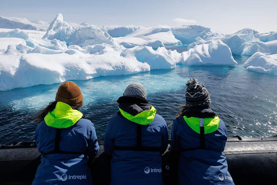 Travellers on a zodiac ride with icebergs in the background, Antarctica