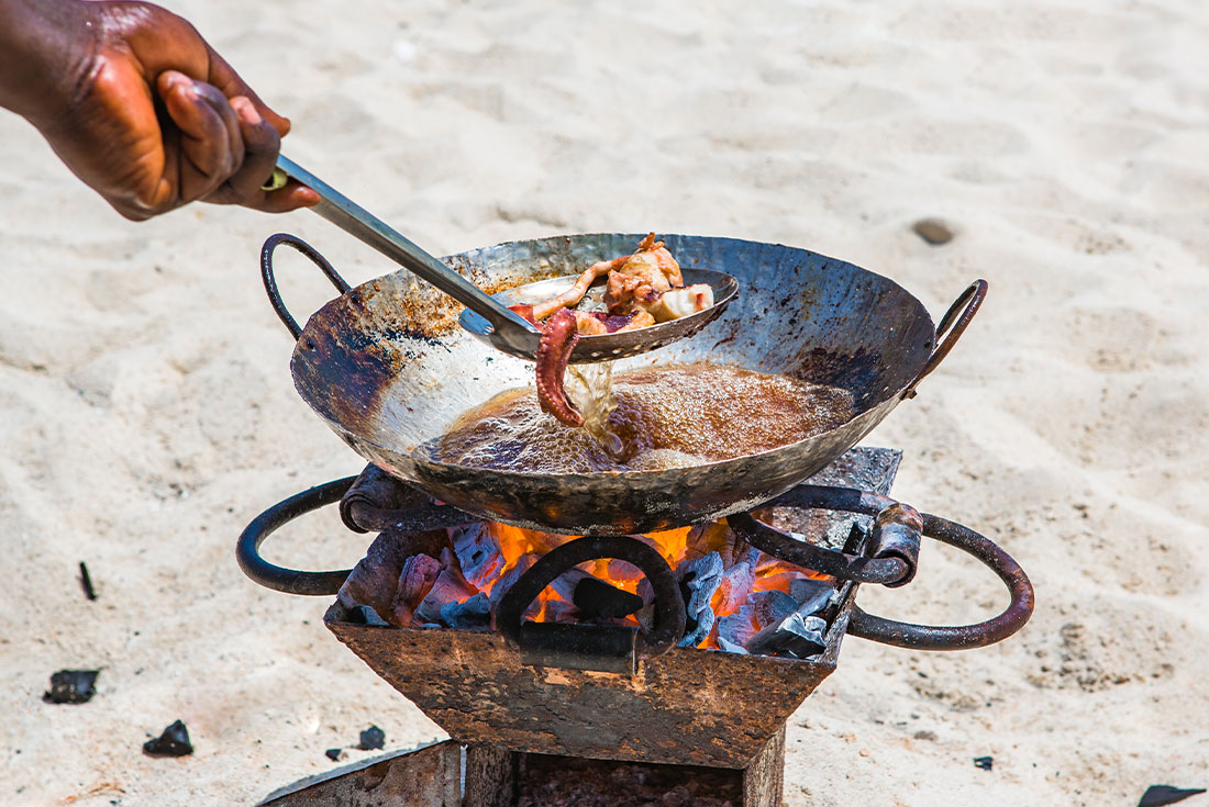 Local cooks seafood over coals on the beach in Zanzibar
