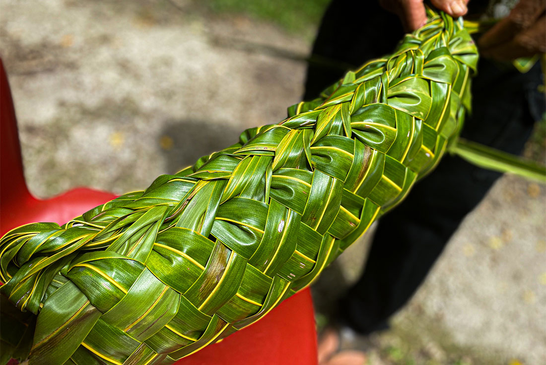 Man makes an intricate braided weave of leaves in traditional fashion