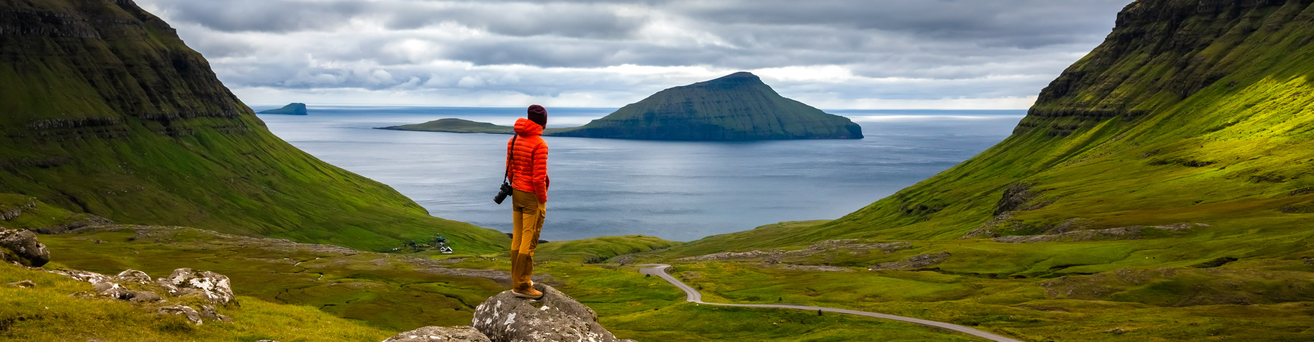 Man in front of a mountain landscape in the Faroe Islands, Denmark, on a cloudy day 