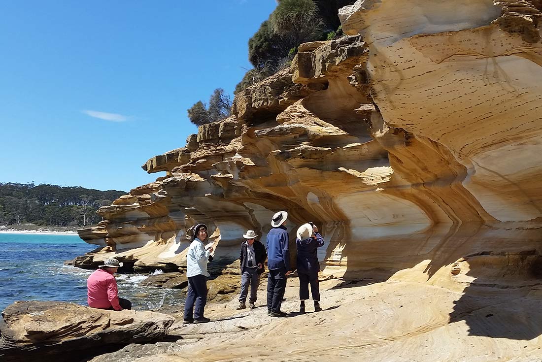 Hikers exploring the Painted Cliffs on Maria Island, Tasmania, Australia