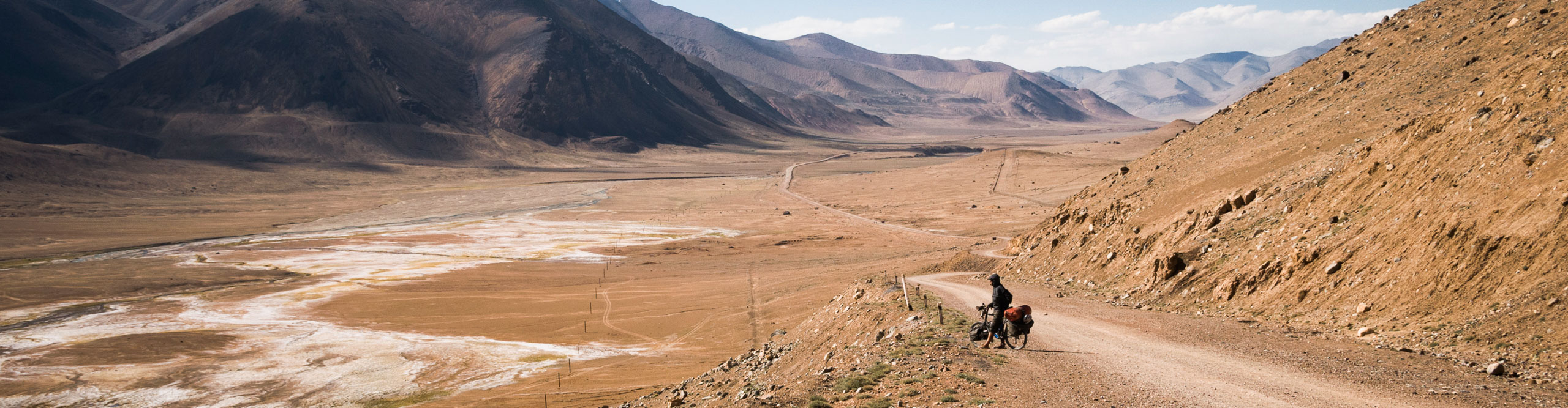 A cyclist on a journey looking at the scenery of the Pamirs of Tajikistan, after the Ak-Baital pass 