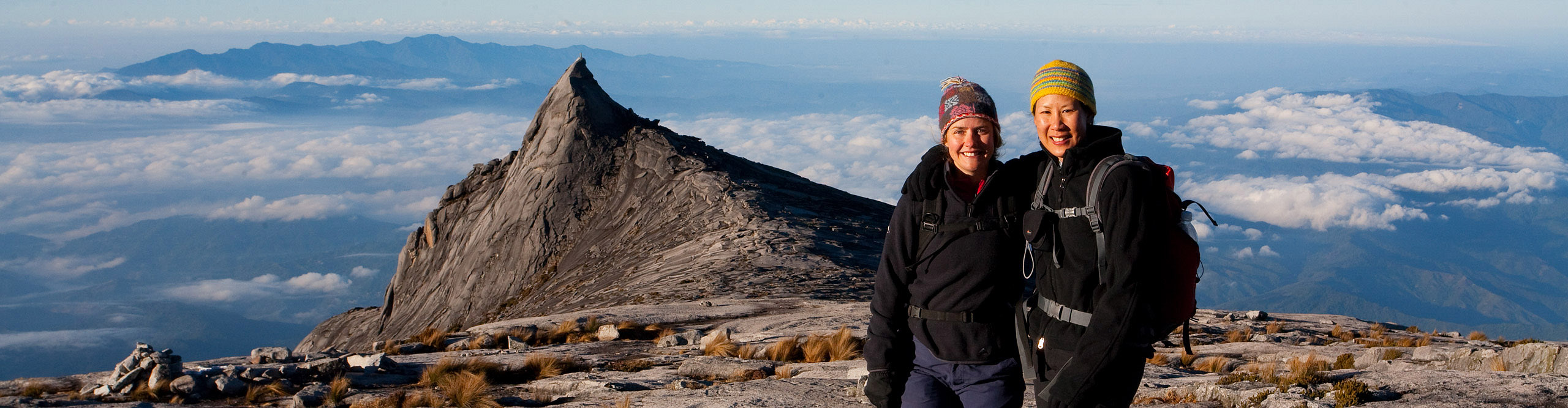 Climbers smiling at the summit of Mount Kinabalu, in Borneo, on a clear sunny day