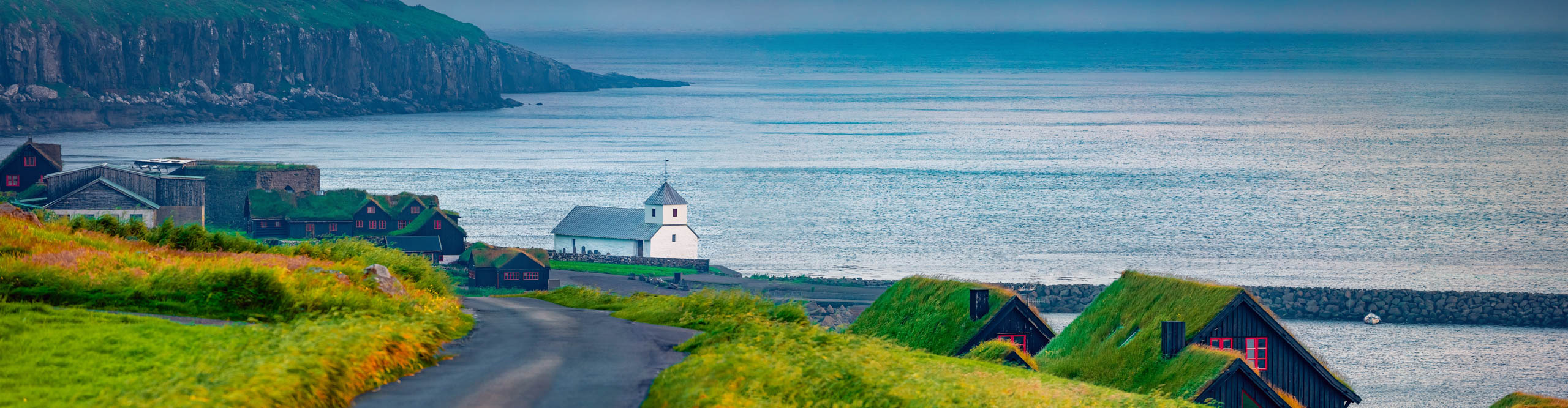 Coastal road going past a small church on the coast of the Faroe Islands 