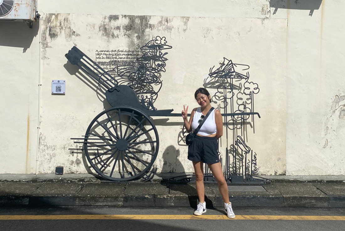 Traveller posing with wire sculpture and street art in Georgetown, Penang