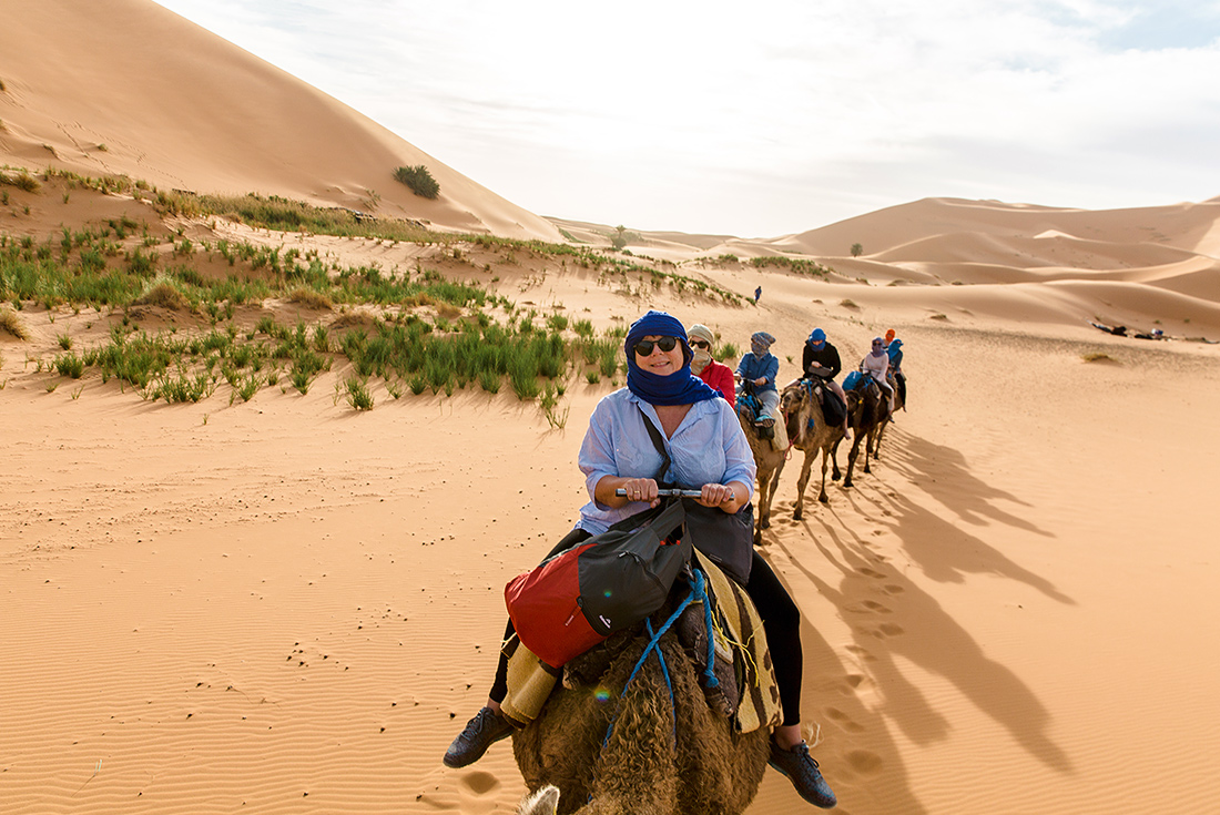 Travellers ride camels through Sahara Desert, Morocco