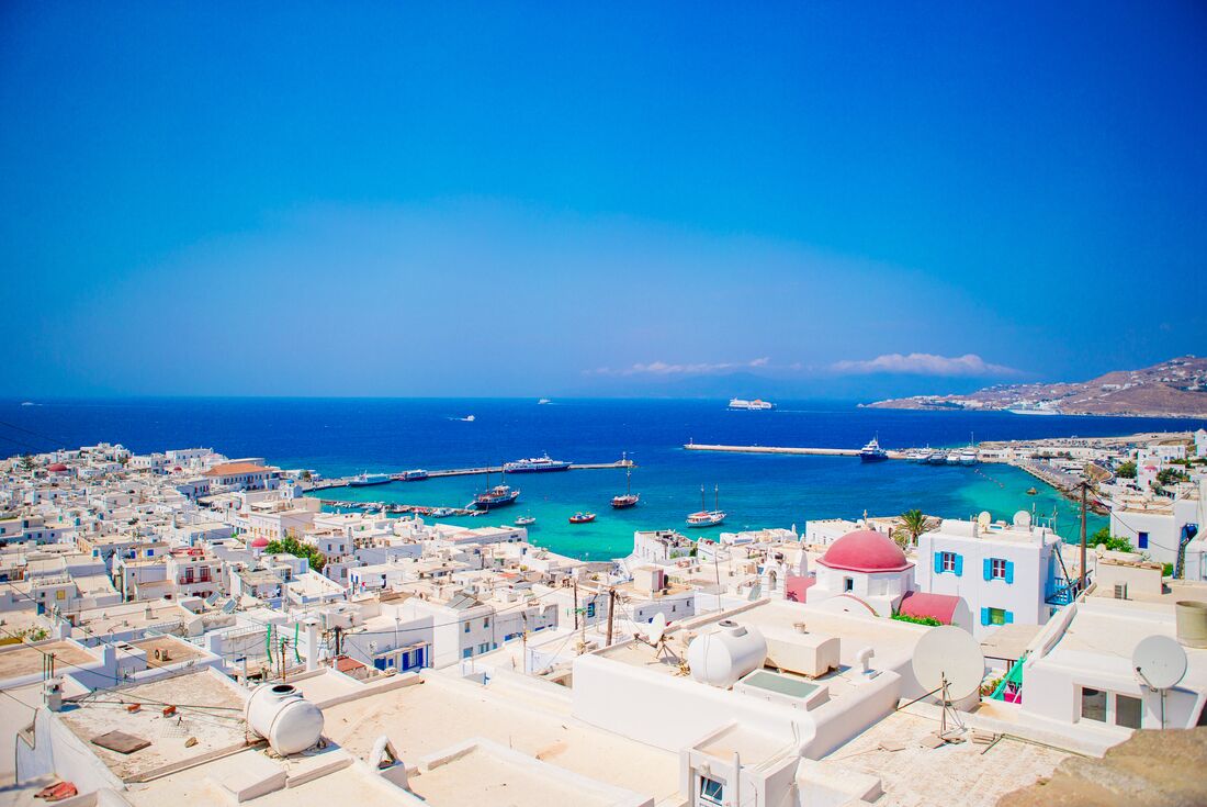 Looking out over Mykonos the pale rooftops with blue and pink tops in the Aegean sea in Greece