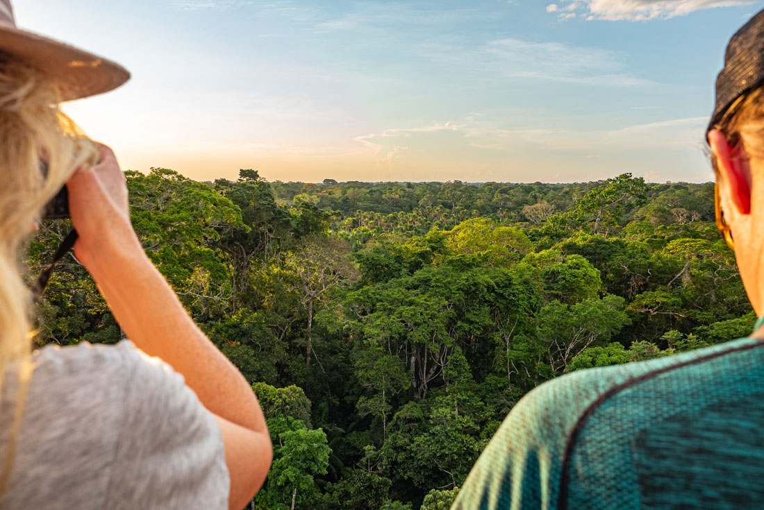 Intrepid travellers look out at the Amazon Rainforest at sunset in Puerto Maldonado