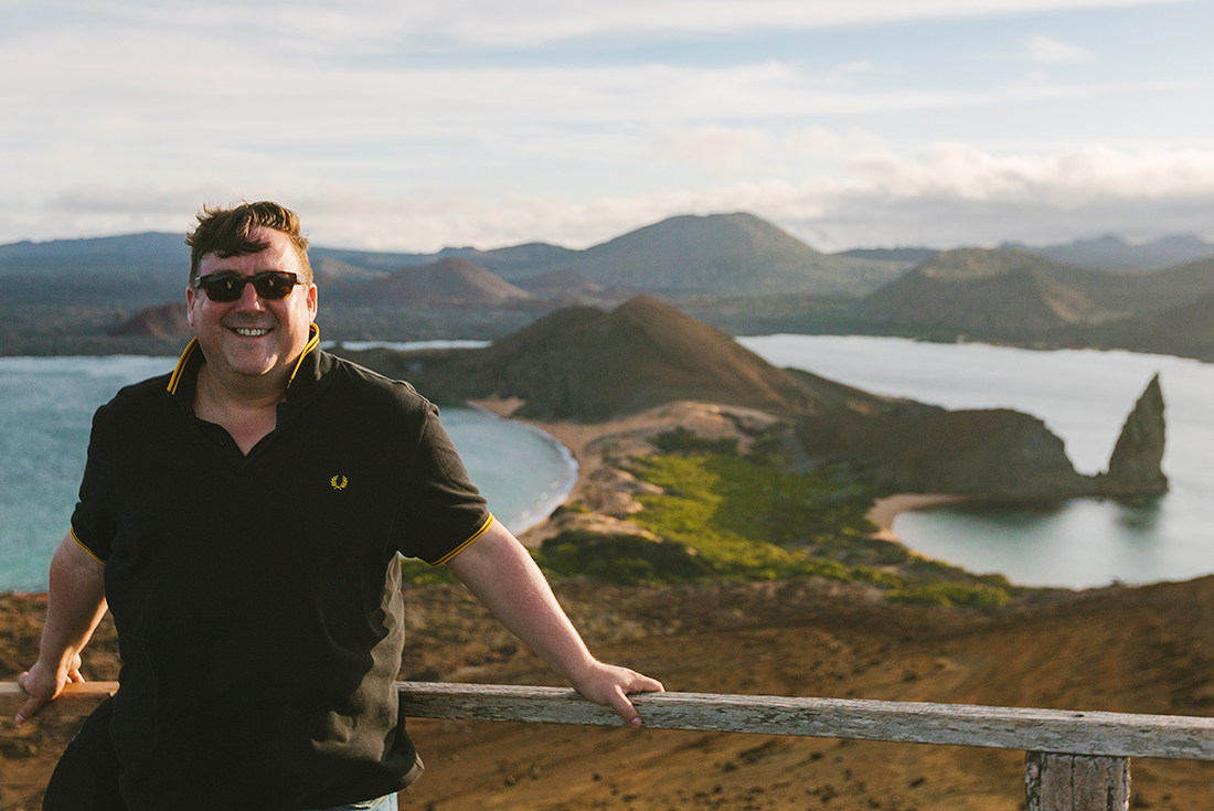 Traveller smiling in front of scenic view, Isla Bartolome, Galapagos Islands