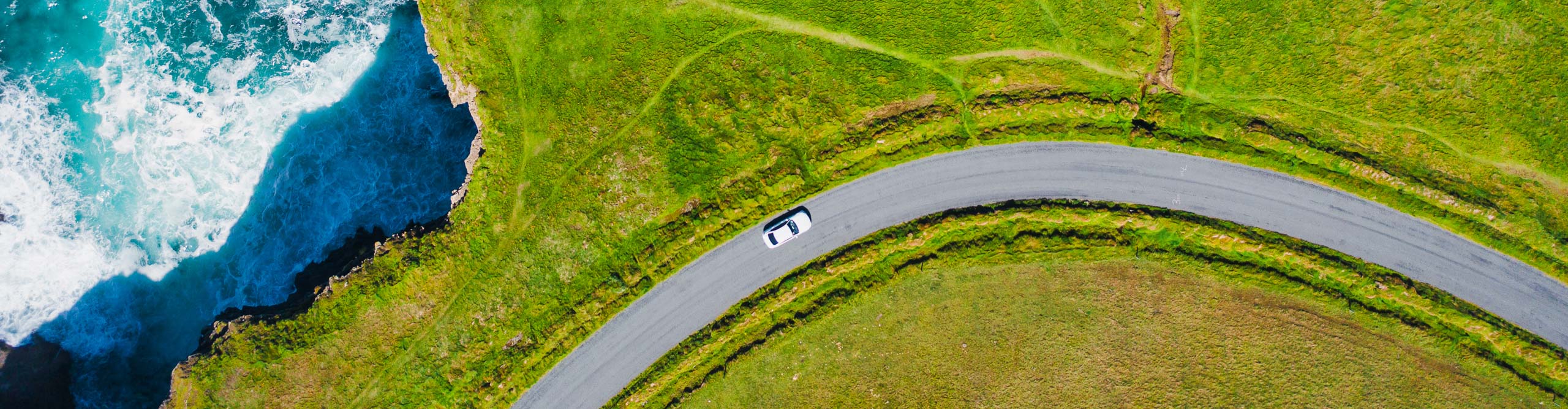 drone shot of car on road near cliffs in Ireland 
