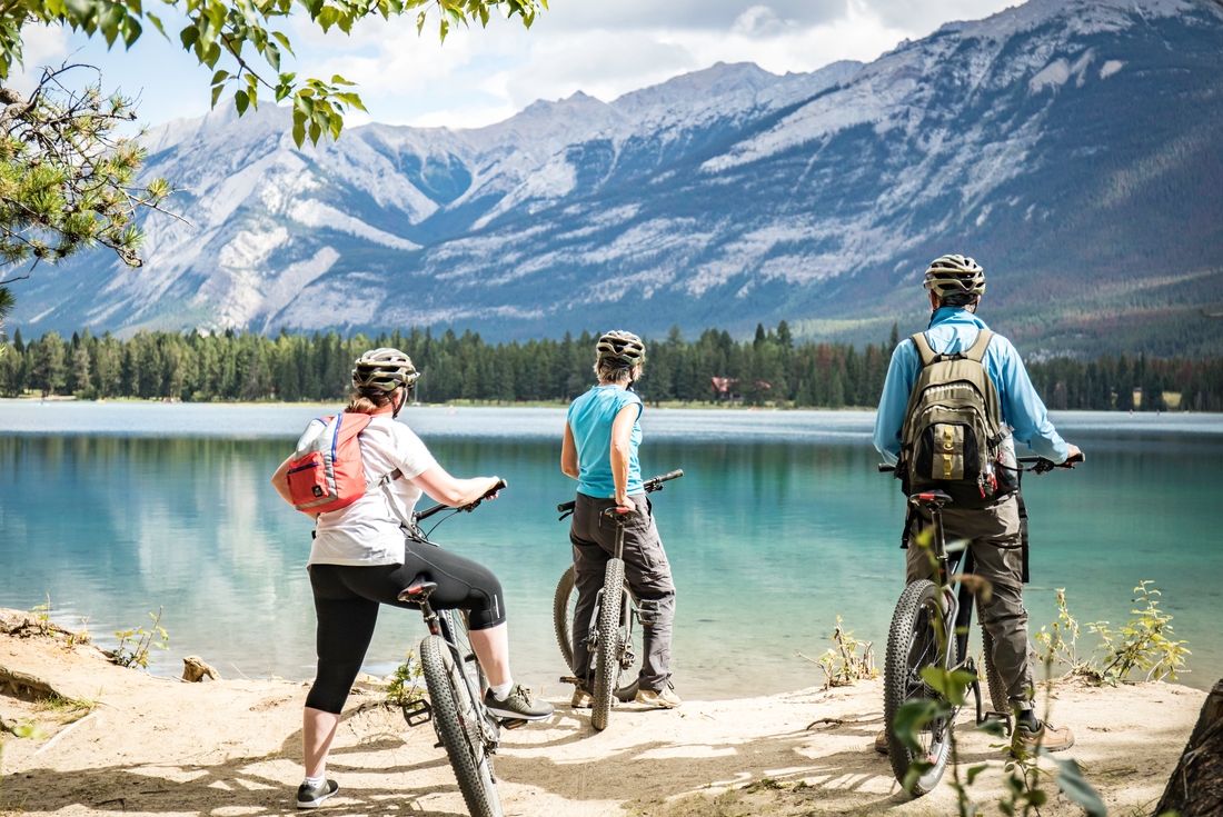 Travellers pausing on their cycling day tour at Edith Lake in Jasper, Canada on an Intrepid Travel tour.