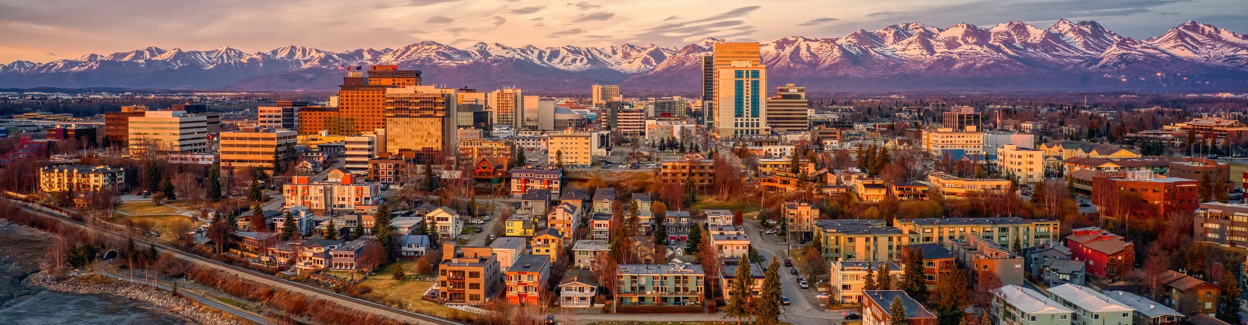 Aerial View of a Sunset over Downtown Anchorage, Alaska in Spring, with snow on the mountains