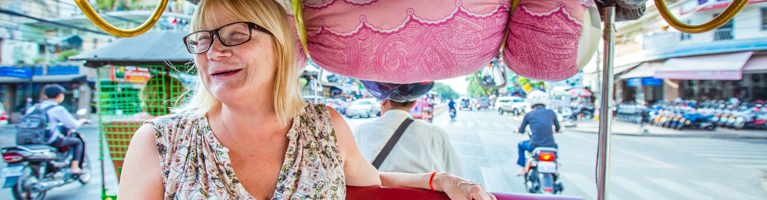 Woman smiling whilst riding in Tuk Tuk through the streets of Phnom Penh, Cambodia 