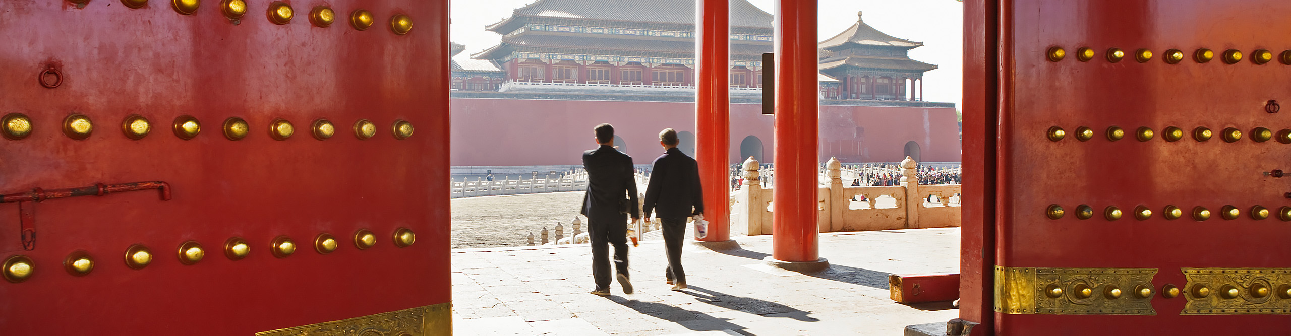 Two men walk through a gatehouse in the Forbidden City on a sunny day in Beijing 