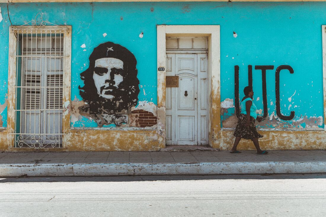 Colourfully painted streets of Trinidad with graffiti of Che Guevara as pedestrian walks by