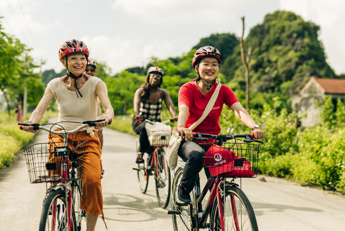 Group of Intrepid travellers and leader with happy faces cycling in Ninh Binh