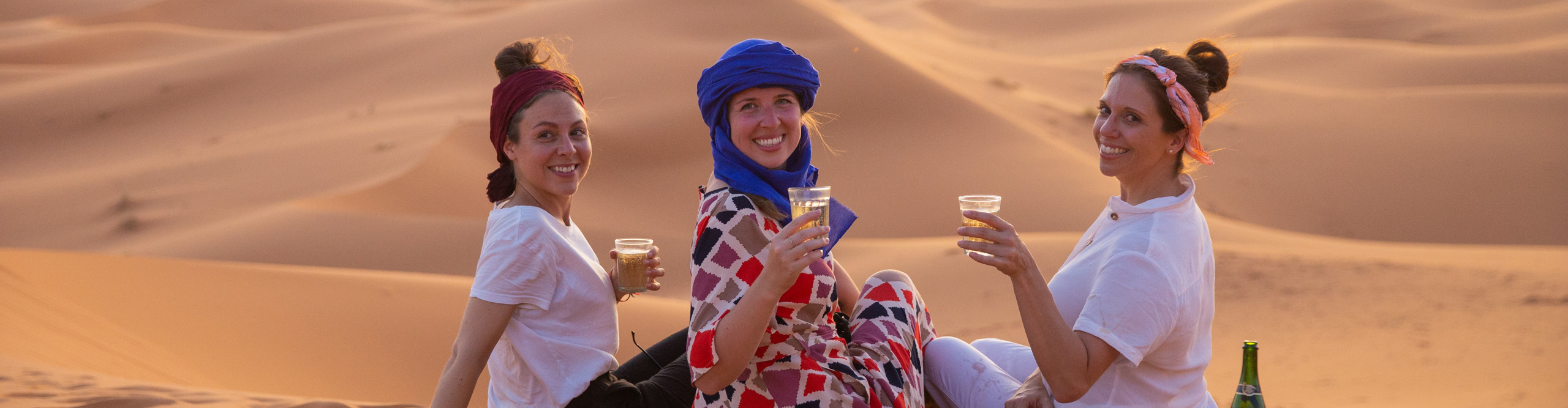 Women drinking wine at sunset in the desert in Morocco