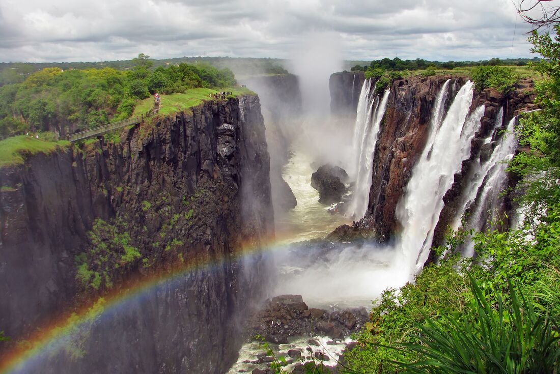 Rainbow forms over waterfall gorge in Victoria Falls