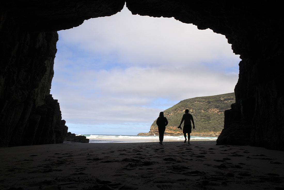 PUKH - Silhouette of travellers walking through Remarkable Cave