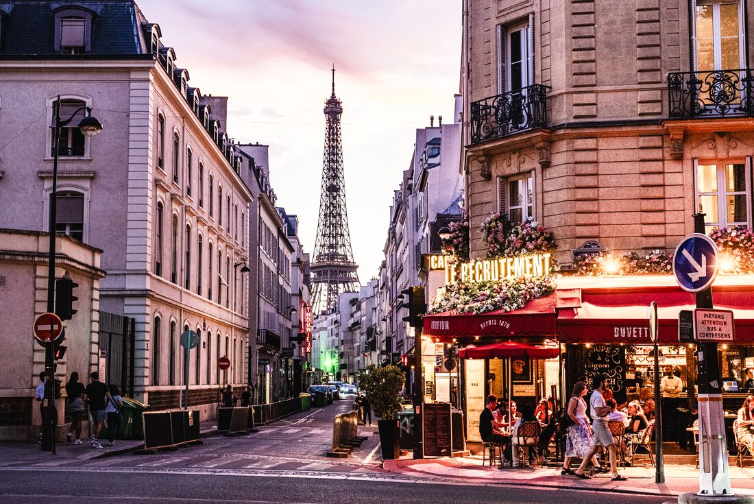 Brightly lit cafes on the streets of Paris in the evening light, Eiffel Tower visible in background