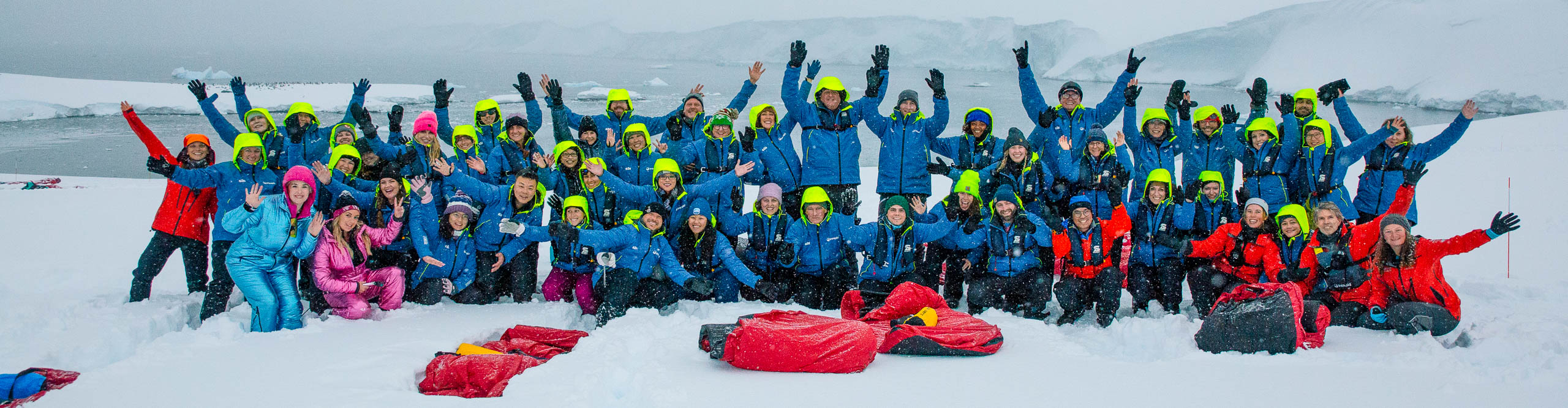 Group posing for photo on the ice with tents in Antarctica 