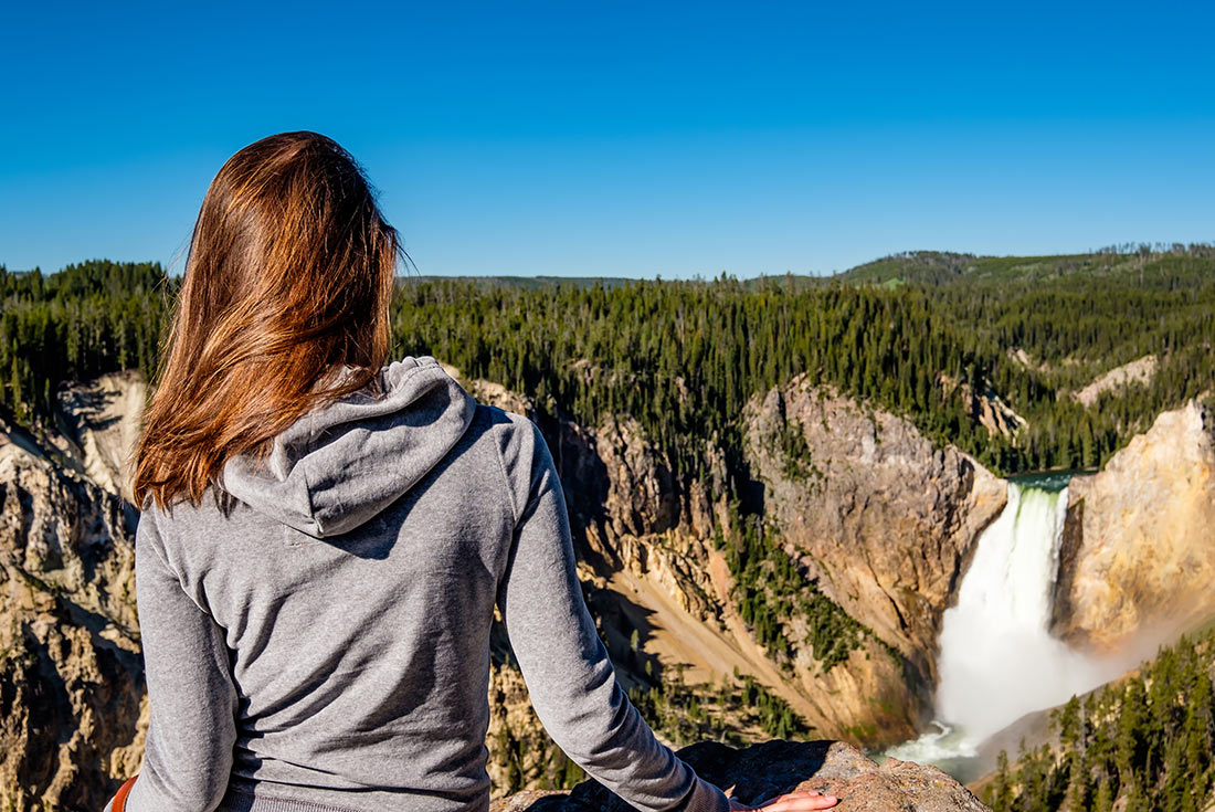 SASY - Tourist looking over waterfall in Yellowstone National Park