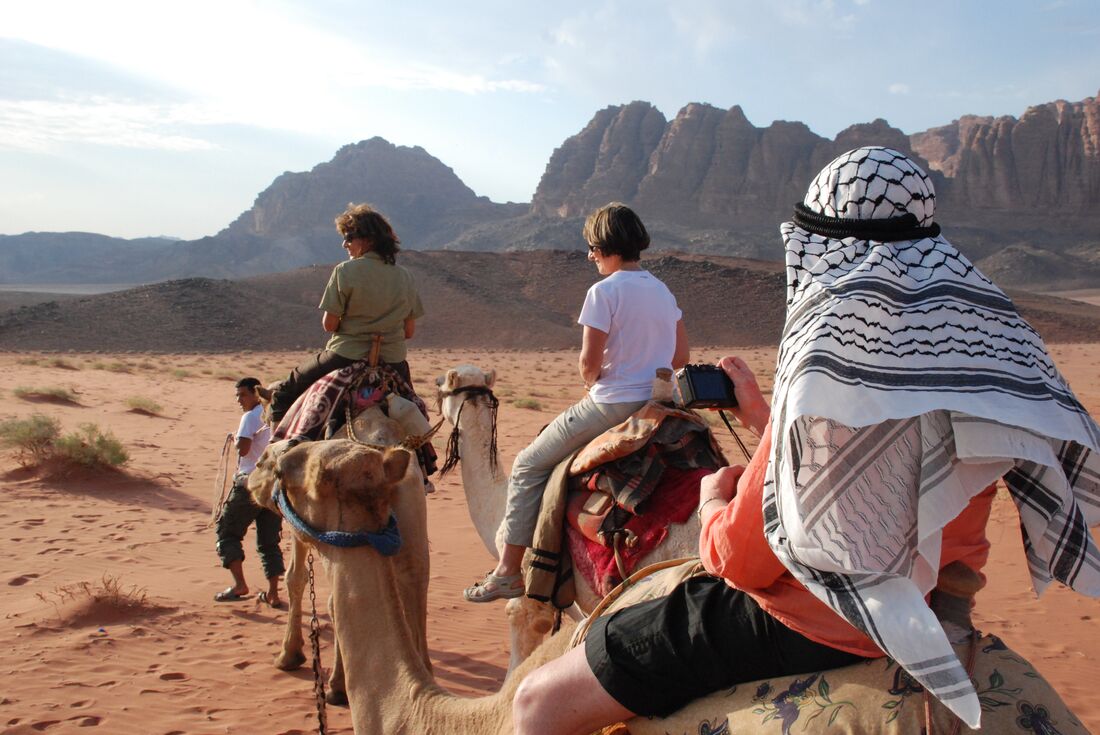 Travellers go on camel ride through Wadi Rum
