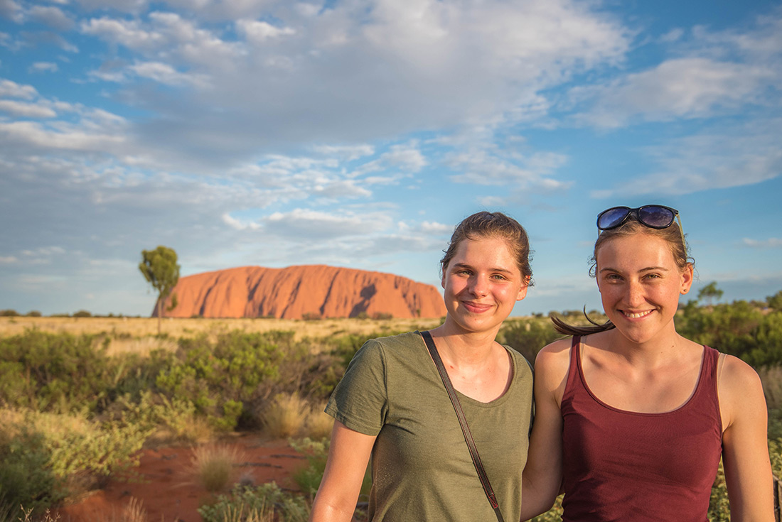 Two female travellers posing in front of Uluru