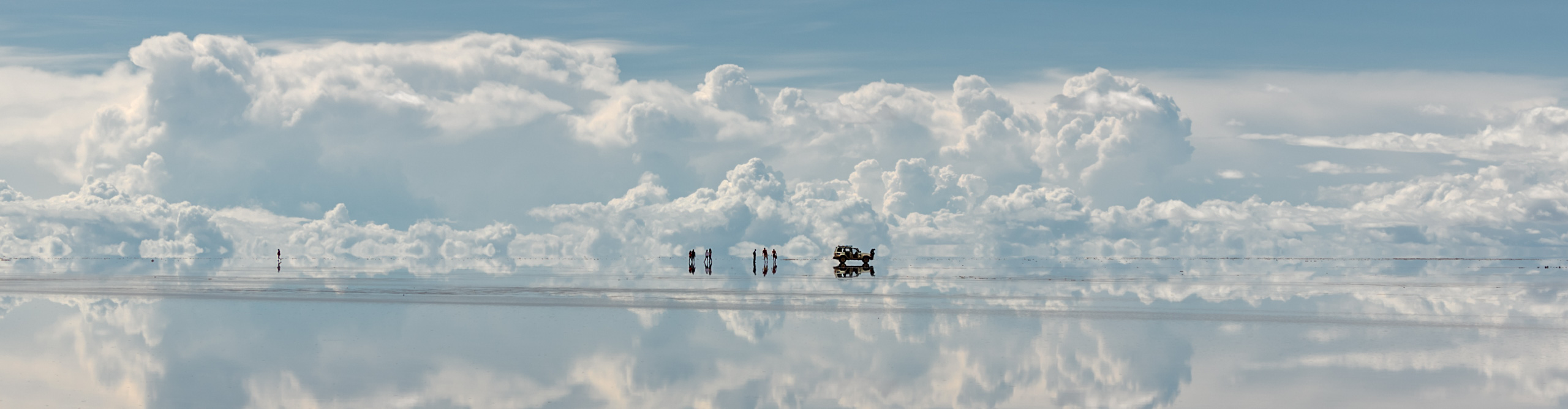 Travellers and 4WD in the middle of the Uyuni Salt Flats in Bolivia