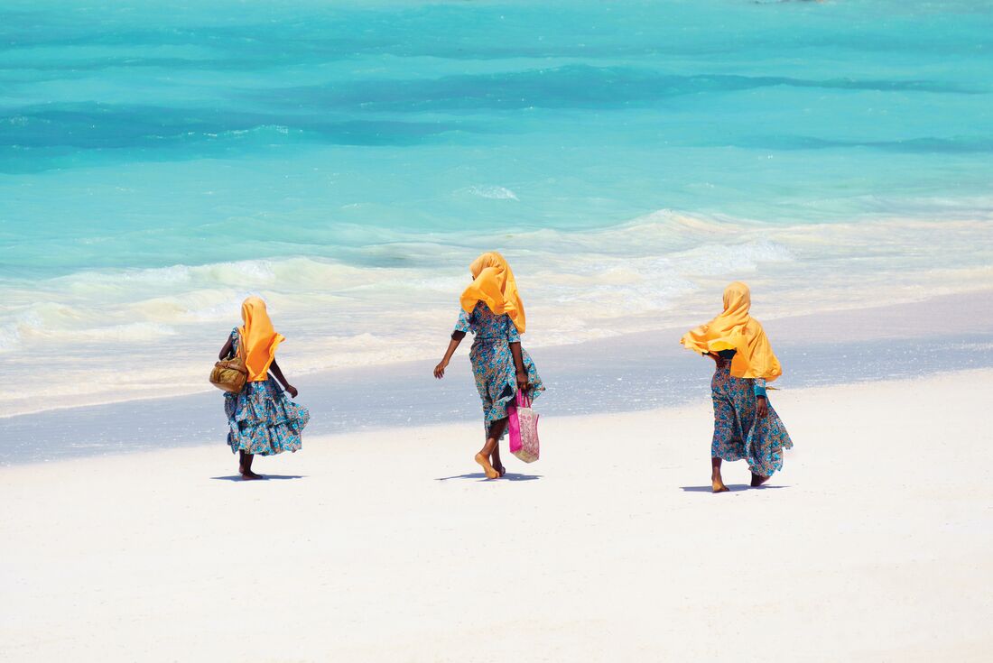 three locals walk the white sands of Zanzibar
