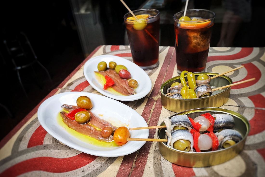Spanish tapas Barcelona style. Vermouth, olives, anchovies served on typical tiled table