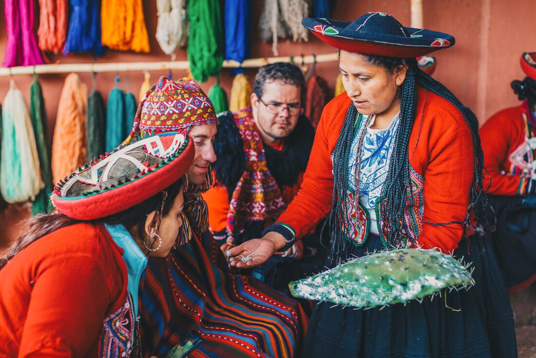 Travellers learning traditional wool dyeing and weaving techniques from local woman, Sacred Valley, Peru