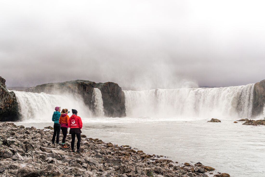 Travellers and leader look upon the Goðafoss waterfall
