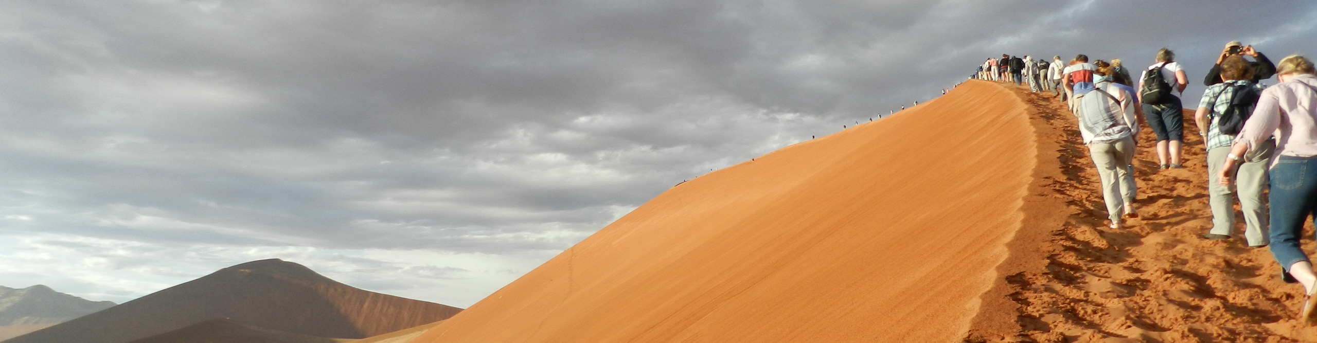 Group climb the dunes in Namibia on a cloudy day, Africa