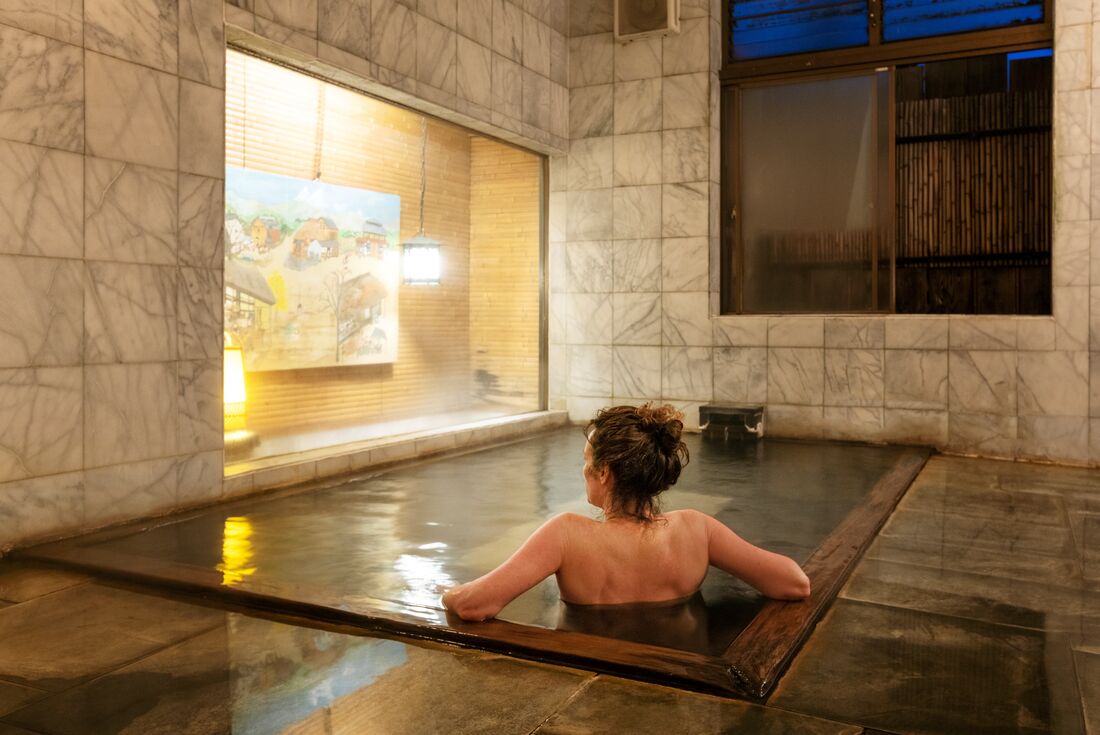 Intrepid traveller relaxes in the natural hot spring waters of an indoor onsen in Yudanaka, in Japan