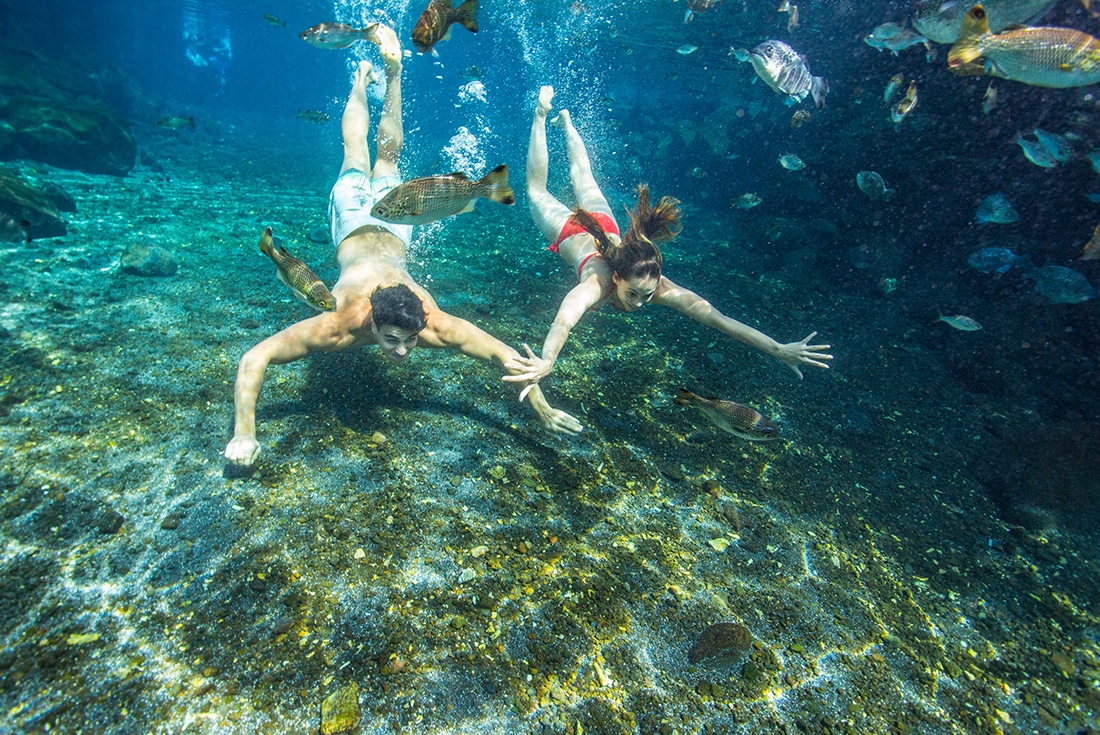 Two passengers swimming in a crystal clear cave pool in Samoa