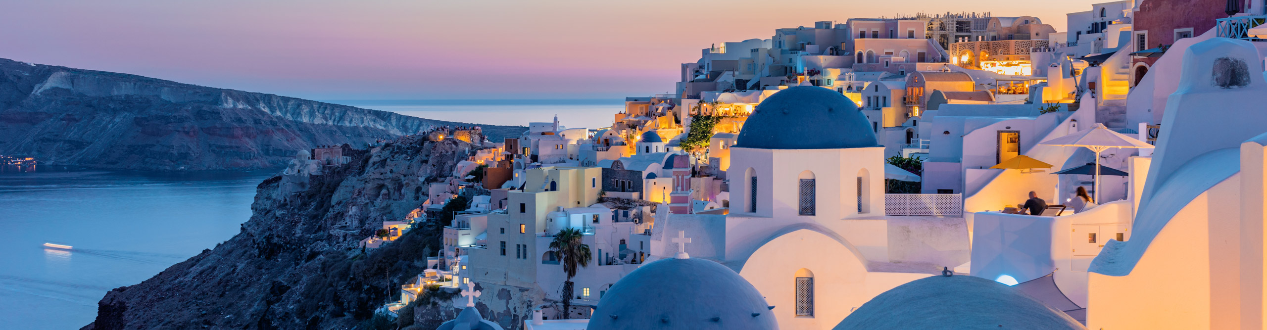 Houses and churches with blue roofs during twilight, Santorini Island, Cyclades, Greece. 