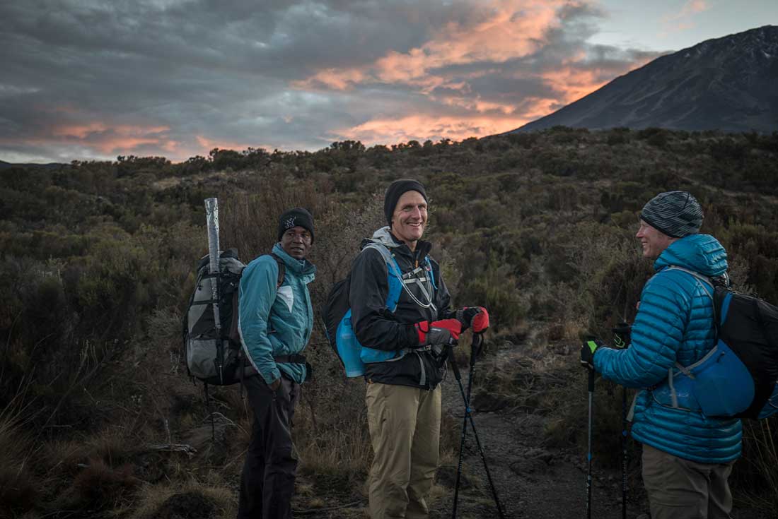 Hikers trek towards Mount Kilimanjaro at sunrise