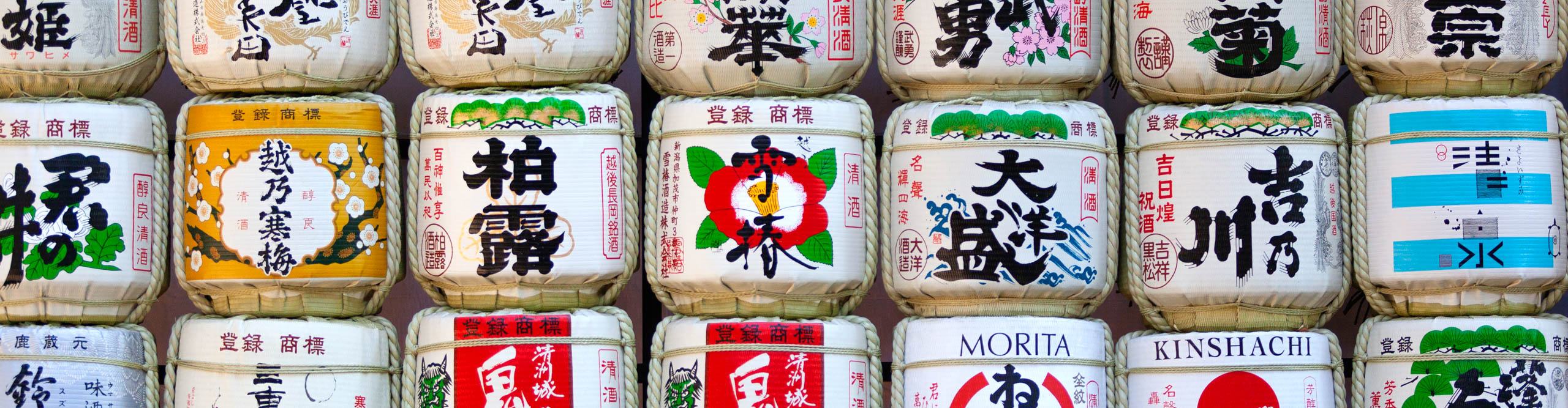 Saki barrels on display covered in Japanese writing and pictures of flowers
