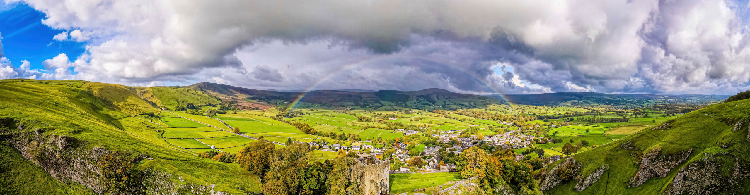Rainbow and dark clouds over the hills of the Peak District and Peveril Castle, England 