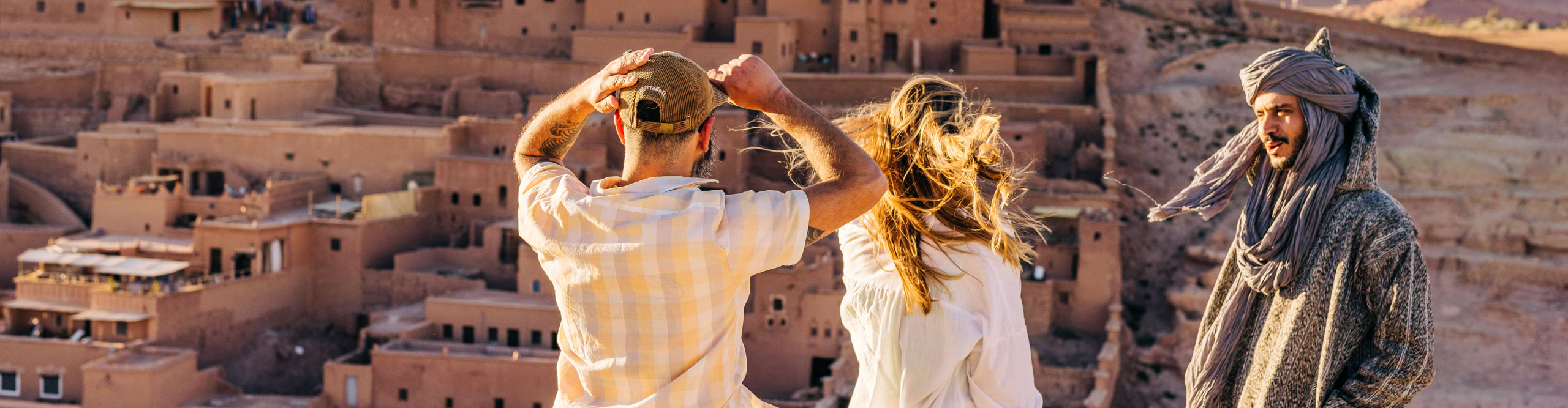 Couple talking with guide in front of Benhaddou, a town built into the hill with clay in Morocco 