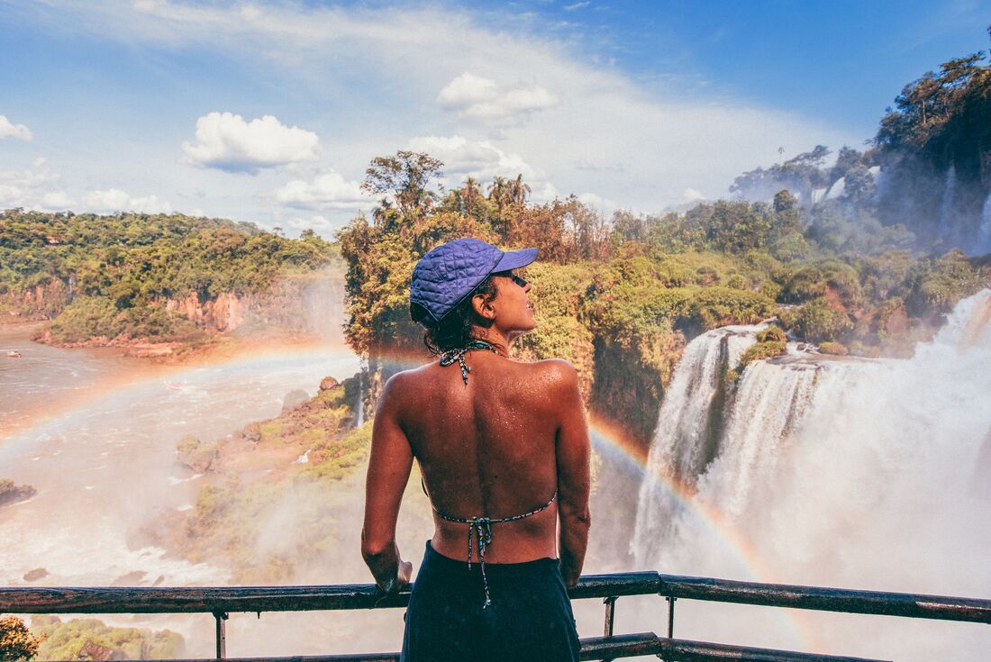 Intrepid traveller 18 to 35 marvelling at the surroundings of Iguazu falls as a rainbow arches in front