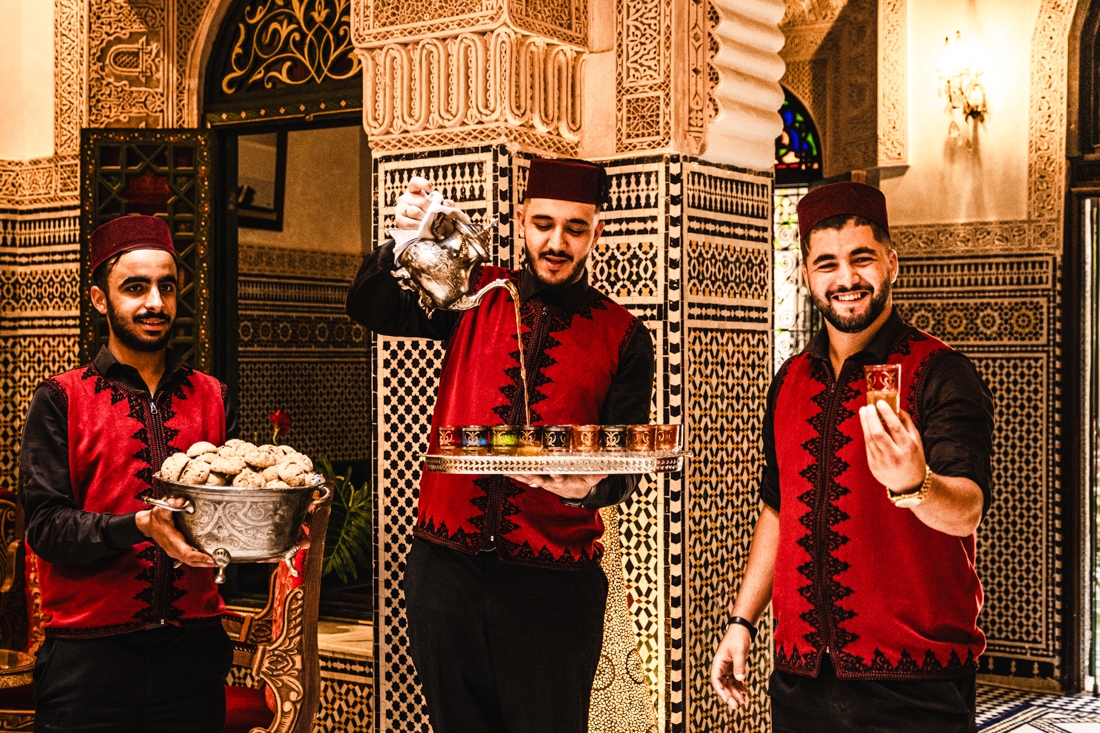 Three hotel staff welcome Intrepid travellers with fresh mint tea and cookies in Fes, Morocco