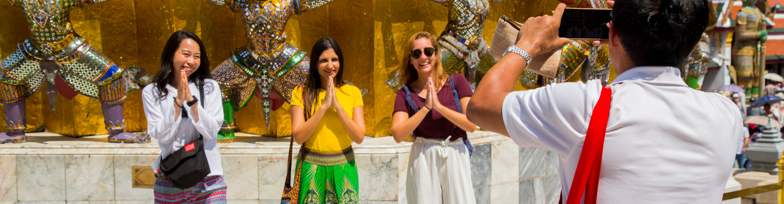 Tourists having their picture taken in front of a temple in Bangkok, Thailand, on a sunny day